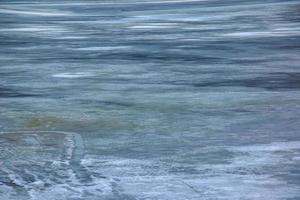 Winter background of the icy surface of the river. Texture of ice covered with snow. photo