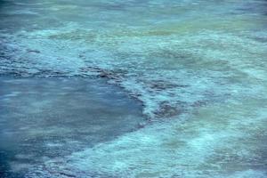 Winter background of the icy surface of the river. Texture of ice covered with snow. photo