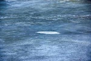 Winter background of the icy surface of the river. Texture of ice covered with snow. photo