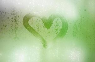 The heart is painted on the misted glass in winter photo