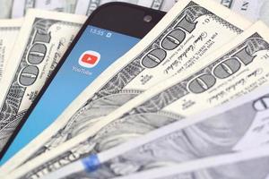 Smartphone screen with Youtube app and lot of hundred dollar bills. Business and social networking concept photo