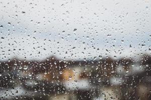 ver a través del vidrio de la ventana mojado por la lluvia, gotas de agua, clima otoñal aburrido, espacio de copia foto