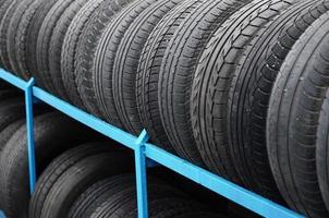 Rack with variety of car tires in automobile store. Many black tires. Tire stack background photo