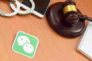 Wechat paper logo lies with wooden judge gavel, smartphone and handcuffs. Entertainment lawsuit concept photo