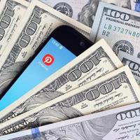 Smartphone screen with Pinterest app and lot of hundred dollar bills. Business and social networking concept photo