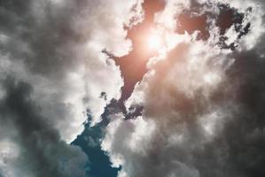 Sun shines through storm clouds, dramatic sky scenery with thunderclouds up above photo