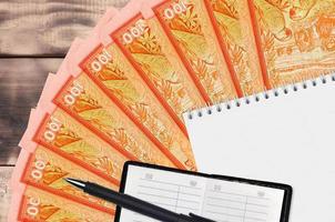 Ventilador de billetes de 100 rupias de Sri Lanka y bloc de notas con libreta de contactos y bolígrafo negro. concepto de planificación financiera y estrategia empresarial foto