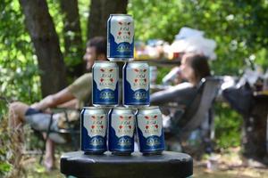 1664 Blanc logo on beer cans in big pile with fishermans on background. 1664 Blanc is the wheat beer from the French brewery Kronenbourg exported worldwide photo