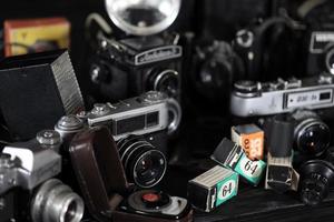 KHARKOV, UKRAINE - APRIL 27, 2021 Film photo cameras and another old retro photo equipment on black wooden table in photographer darkroom. Photographic gear from soviet union