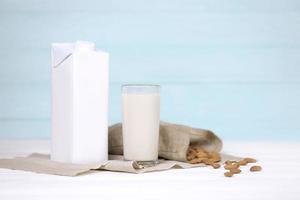 vaso de leche de almendras con nueces de almendras sobre tela de lona sobre mesa de madera blanca. leche alternativa láctea para desintoxicación, alimentación saludable y dietas foto