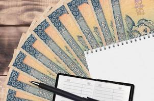 Ventilador de billetes de 5 hryvnias ucranianas y bloc de notas con libreta de contactos y bolígrafo negro. concepto de planificación financiera y estrategia empresarial foto