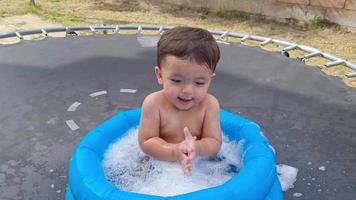 schattige 1-jarige Pakistaanse Aziatische babyjongen geniet in een waterbad. video