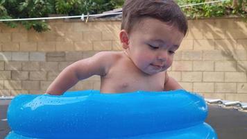 bonito bebê asiático paquistanês de 1 ano está desfrutando na banheira de água. video