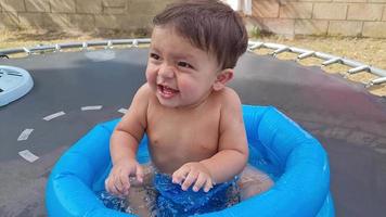 il simpatico bambino asiatico pakistani di 1 anno si sta godendo nella vasca d'acqua. video