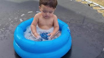 schattige 1-jarige Pakistaanse Aziatische babyjongen geniet in een waterbad. video