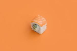 Philadelphia roll with salmon on orange background. Minimalism top view flat lay with Japanese food photo