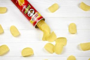 Pringles original flavour. Cardboard tube can with Pringles potato chips on white table. Pringles is a brand of potato snack chips owned by the Kellogg Company photo