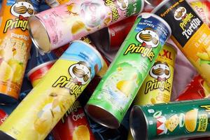 Pringles variety of flavors. Many cardboard tube cans with Pringles potato chips. Pringles is a brand of potato snack chips owned by the Kellogg Company photo