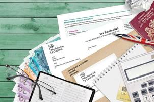 English form sa100 Tax return by HM revenue and customs lies on table with office items. HMRC paperwork and tax paying process in United Kingdom photo