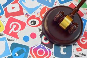 Wooden judge gavel lies on many paper logos of popular social networks and internet resources. Entertainment lawsuit concept photo