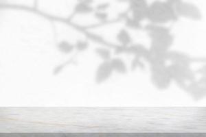 Marble table with tree shadow drop on white wall background for mockup product display photo