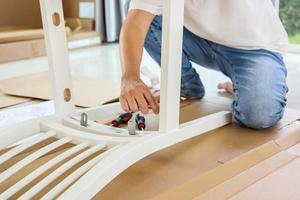 Man assembling white chair furniture at home photo