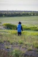 Children in the open spaces of the field are walking among the juicy spring grass in the light of sunset along a narrow trampled path photo
