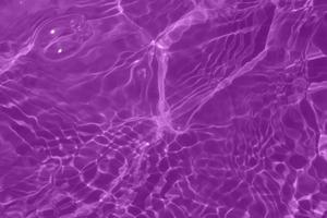 Defocus blurred transparent purple colored clear calm water surface texture with splash, bubble. Shining purple water ripple background. Surface of water in swimming pool. Purple bubble water shine. photo