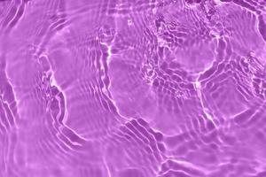 Defocus blurred transparent purple colored clear calm water surface texture with splash, bubble. Shining purple water ripple background. Surface of water in swimming pool. Purple bubble water shine. photo