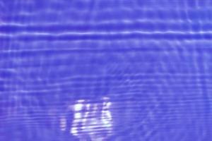 Defocus blurred transparent purple colored clear calm water surface texture with splash, bubble. Shining purple water ripple background. Surface of water in swimming pool. Purple bubble water shine. photo