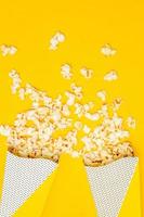 refrigerio de ver el concepto de película, palomitas de maíz dulces flotan de dos vasos de papel sobre fondo amarillo