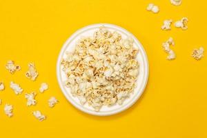 Snack concept, Sweet popcorn in white plate and falling on yellow background