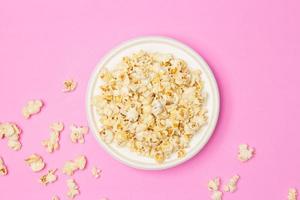 Snack concept, Sweet popcorn in white plate and falling on pink background