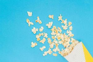 refrigerio de ver el concepto de la película, las palomitas de maíz dulces flotan desde la taza de papel sobre fondo azul claro