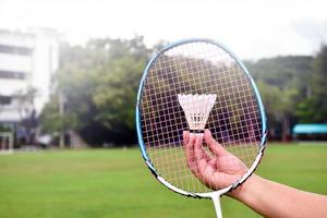 Badminton racket and badminton shuttlecocks holding in hands for outdoor playing, soft and selective focus on string and racket, concept for outdoor activity. photo