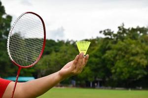 raqueta de bádminton y volantes de bádminton tomados de la mano para jugar al aire libre, enfoque suave y selectivo en cuerdas y raquetas, concepto de actividad al aire libre. foto