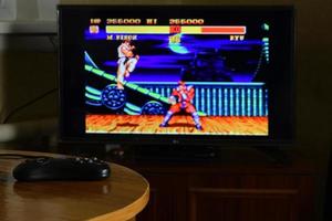 KHARKOV, UKRAINE - NOVEMBER 12, 2020 Sega mega drive video game controller on table with Street Fighter 2 game on display photo