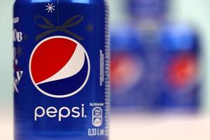 KHARKOV, UKRAINE - DECEMBER 8, 2020 Aluminium cans of Pepsi soft drink on white wooden table. Pepsi is carbonated soft drink produced by PepsiCo was created and developed in 1893 photo