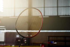 Closeup badminton racket in front of the net before serving it to another side of the court, soft and selective focus. photo