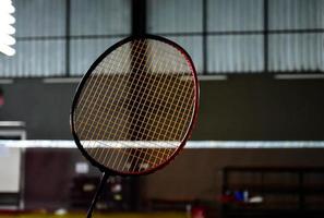 Closeup badminton racket in front of the net before serving it to another side of the court, soft and selective focus. photo