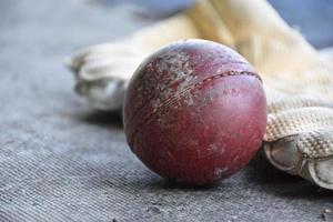 Training cricket sport equipments on floor, leather ball, gloves and bat, soft and selective focus on ball. photo