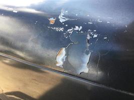 The outside surface of the car's paint is cracked due to deterioration and scratches from various accidents. photo