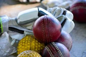 entrenar equipos deportivos de cricket en el piso, pelota de cuero, guantes y bate, enfoque suave y selectivo en la pelota. foto