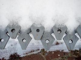 Wooden fence denticles. Items in the snow. photo