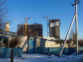 high-rise construction. Urbanization. Old small houses against the background of large high-rise buildings photo