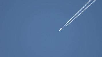 avion de ligne volant haut dans le ciel laissant des traînées dans le ciel bleu clair. video