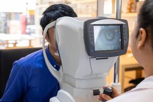 Selective focus at screen of Optometry equipment. While optometrist using subjective refraction to  examine eye visual system of young men patient with professional machine before made glasses. photo