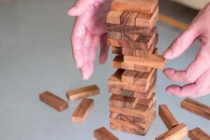 Selective focus at wood brick. Business people using hand to pull out wood brick with caution. taking risk and make decision to play the game. Insurance or financial risk management and safety concept photo