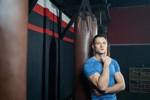 Shirtless handsome Caucasian men boxer with strong muscle training boxing punch in side of the gym with sandbag. Cardio sport workout activity for good health and build up body and physical strength. photo