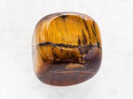 tumbled tiger-eye gem stone on white marble photo